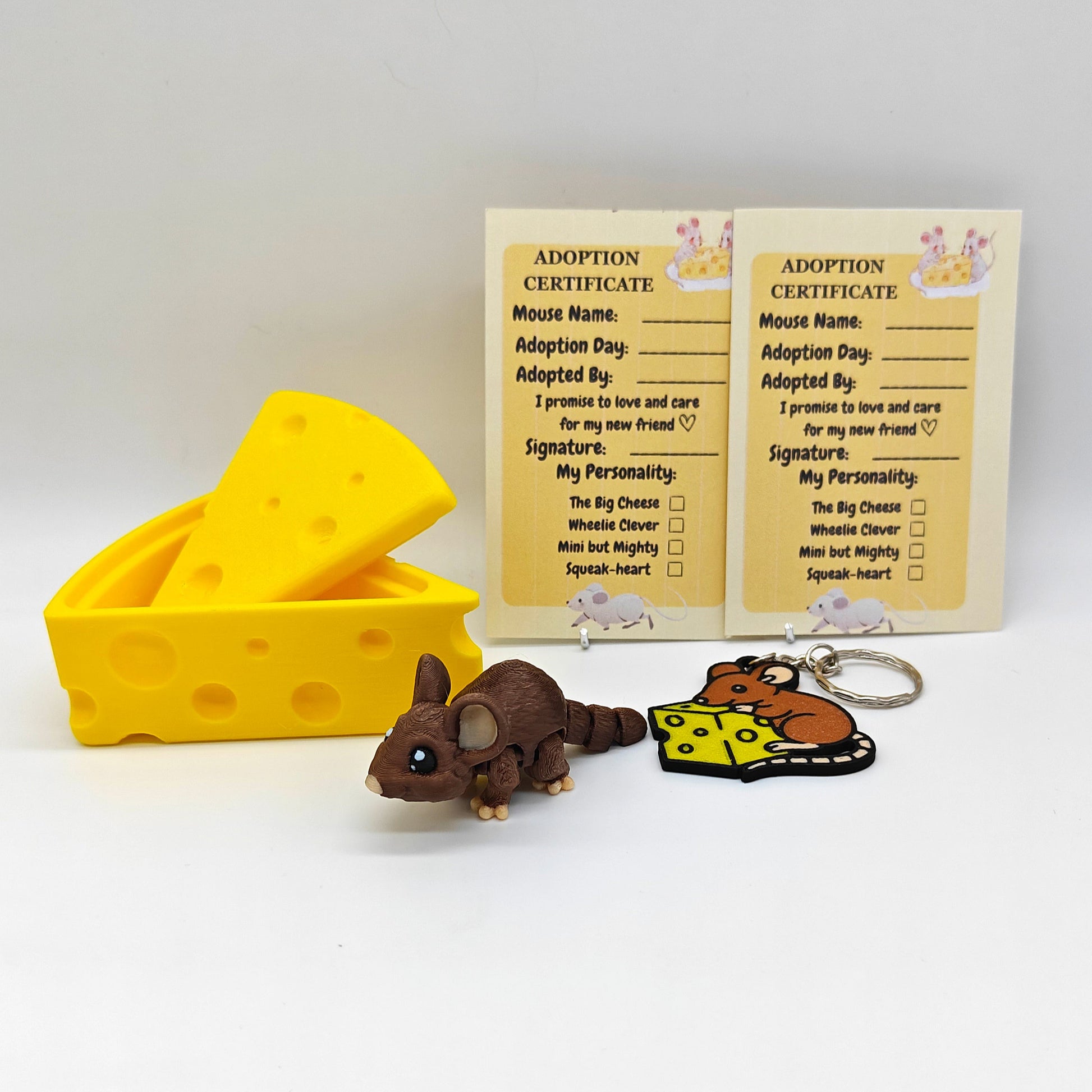 Toy mouse, cheese block, and keychain with adoption certificate on a white background